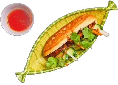 A bánh mì on a woven leaf tray with a small bowl of dipping sauce