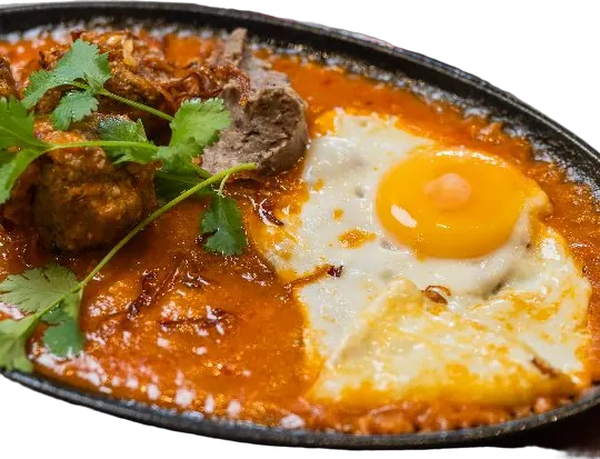 A bánh mì sizzling: a hot iron pan with fried egg, meatballs, pâté and coriander